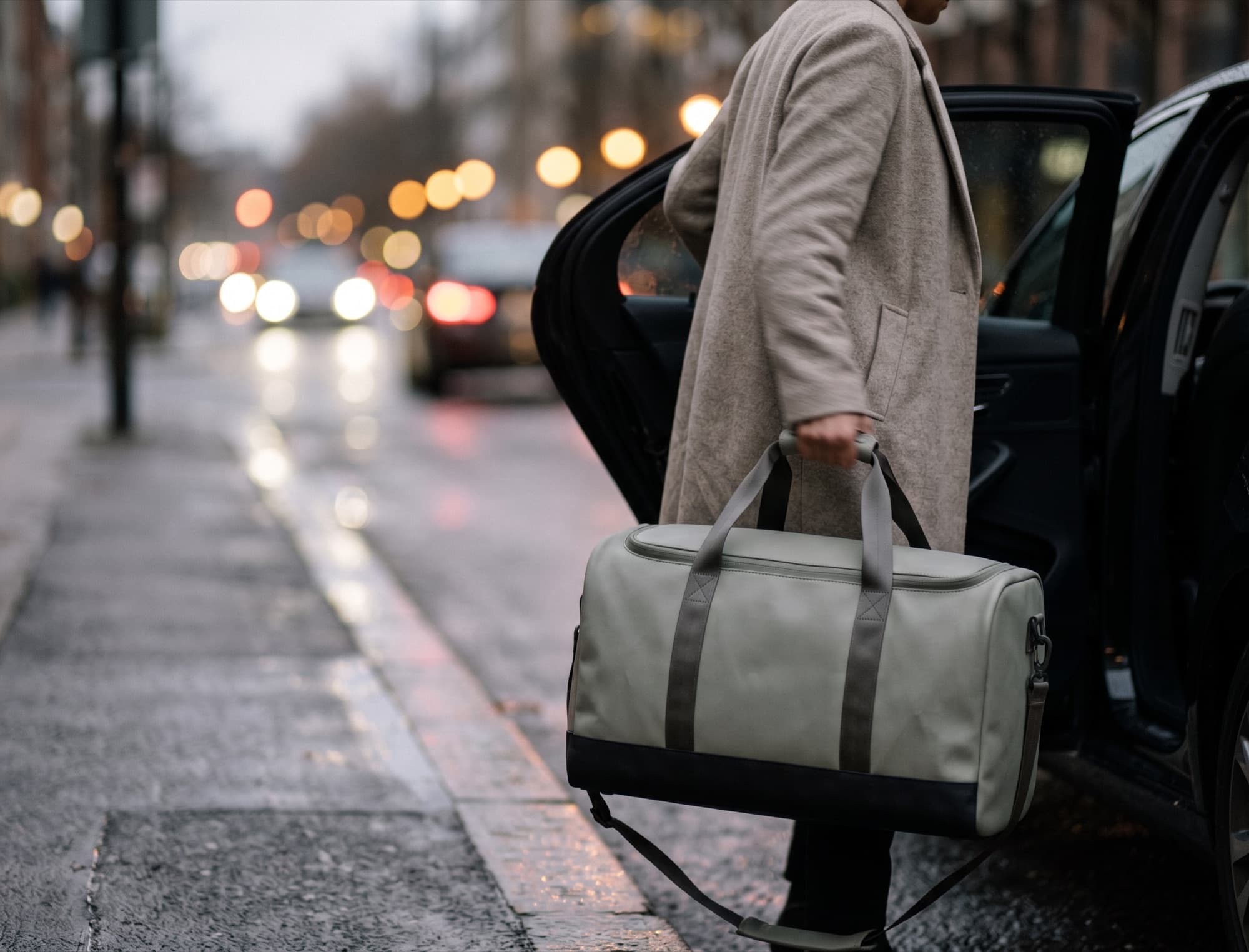 Lifting the duffel from the back of a car at the kerb